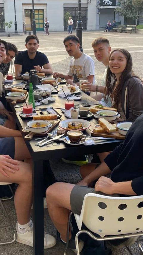 El equipo almorzando en una mesa larga al aire libre en una plaza
