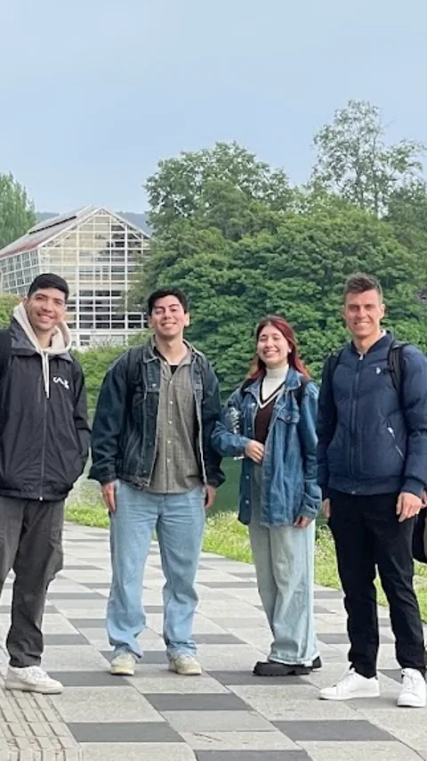 Cuatro personas del equipo caminando frente a un edificio de vidrio junto a un río