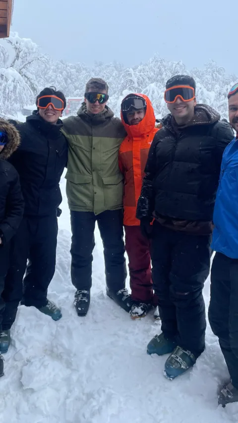 Cinco personas del equipo con ropa de nieve y antiparras, en la montaña