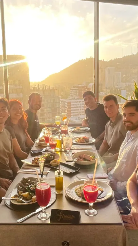 Cena del equipo en un restaurante con ventanales y vista a la ciudad al atardecer